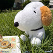 Close up of Andy the Peanuts plush dog with white fur and brown ears on grass