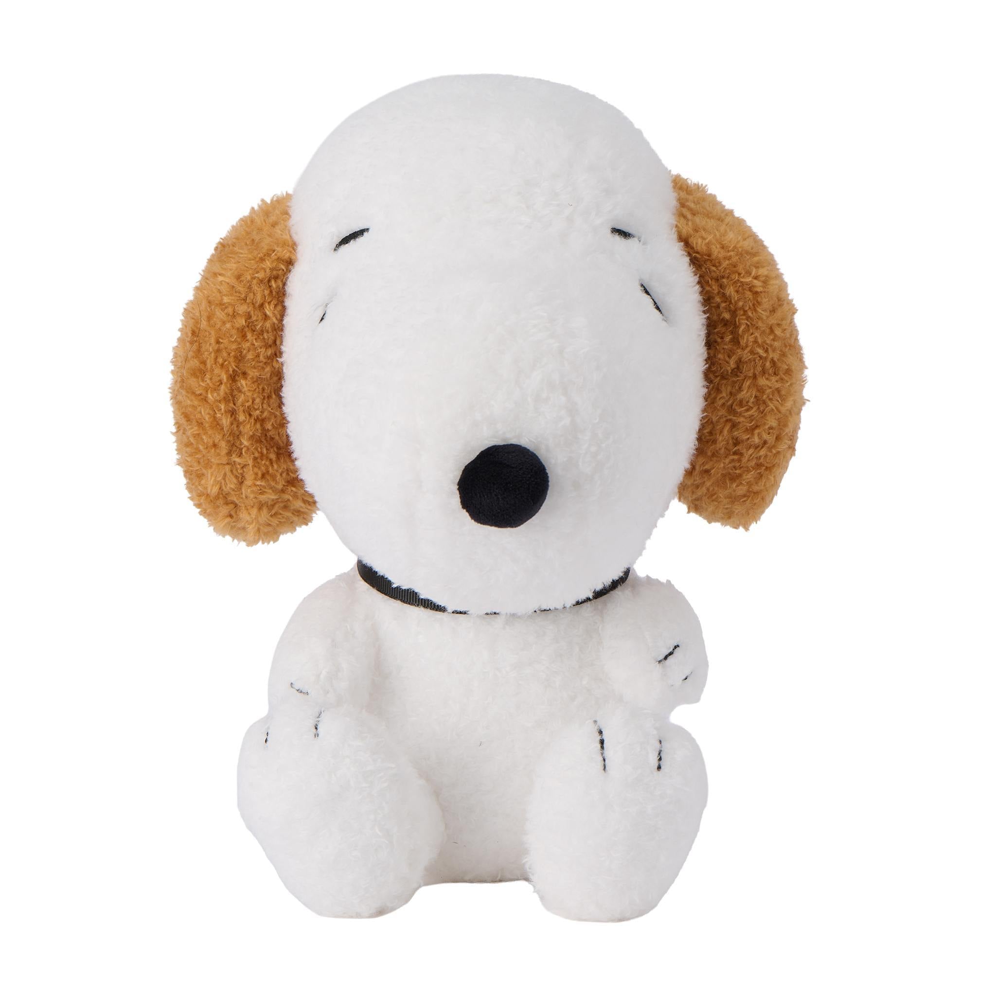Close up of a white Peanuts plush dog head with closed eyes and brown ears