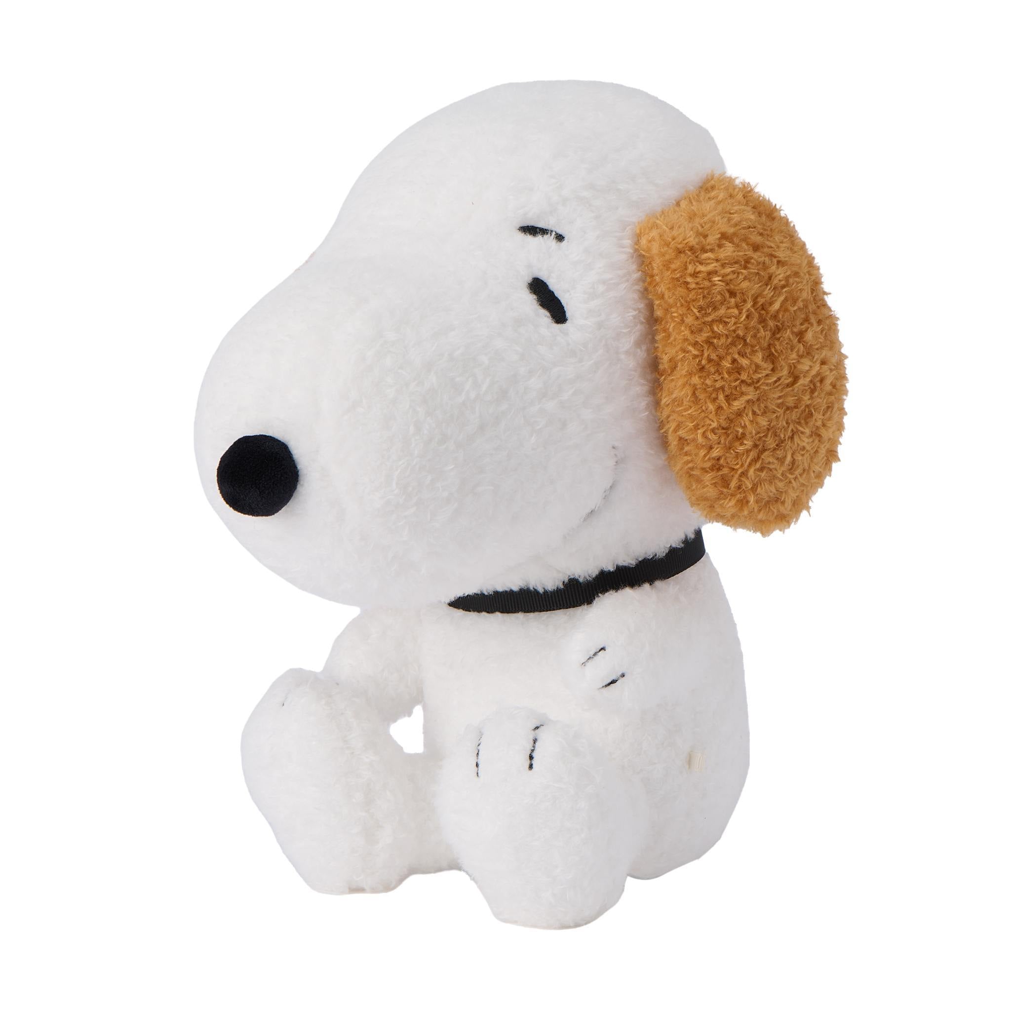 Profile of a white Snoopy plush with a tan fluffy ear and stitched features