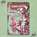 Pink and gray Godzilla toy figure in packaging with cherry blossoms and Mount Fuji on a light green background