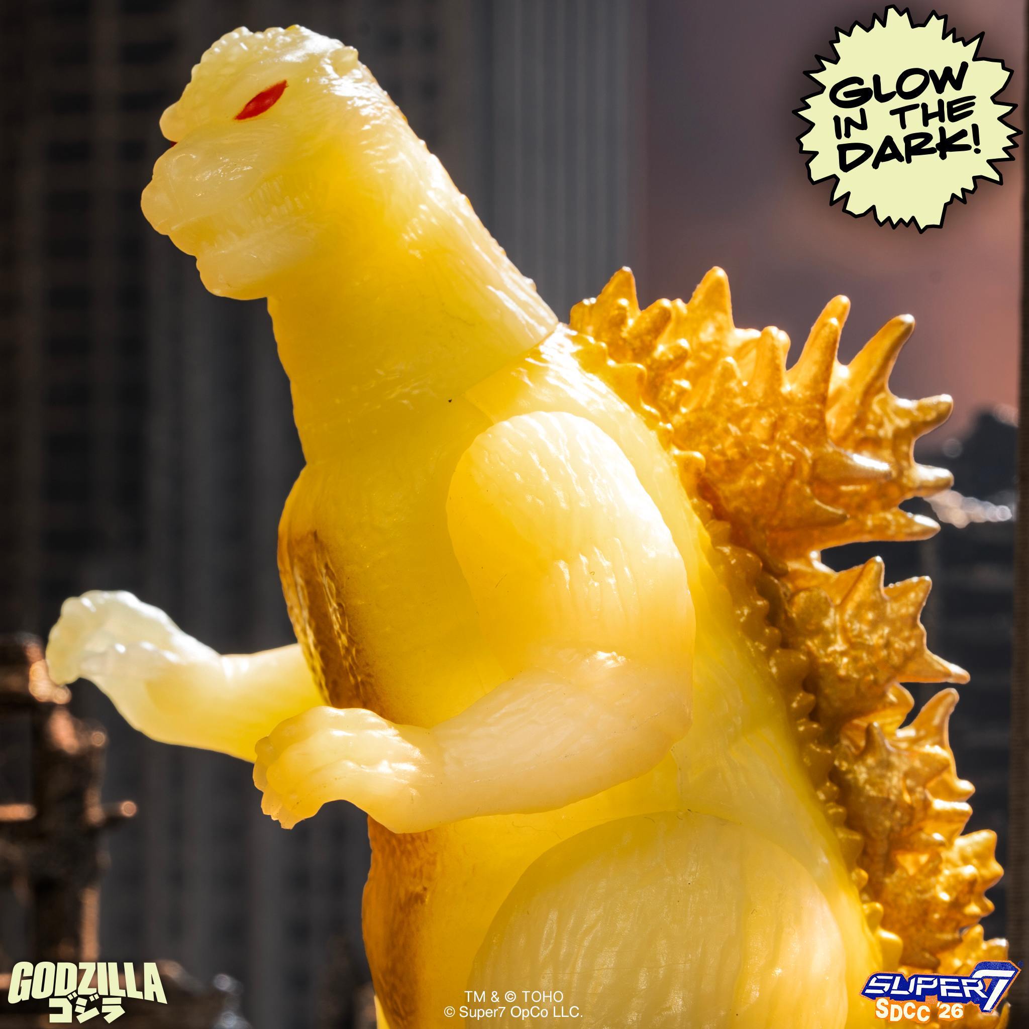Side view of the yellow glow Godzilla figure with orange chest and glow in the dark badge on the right.