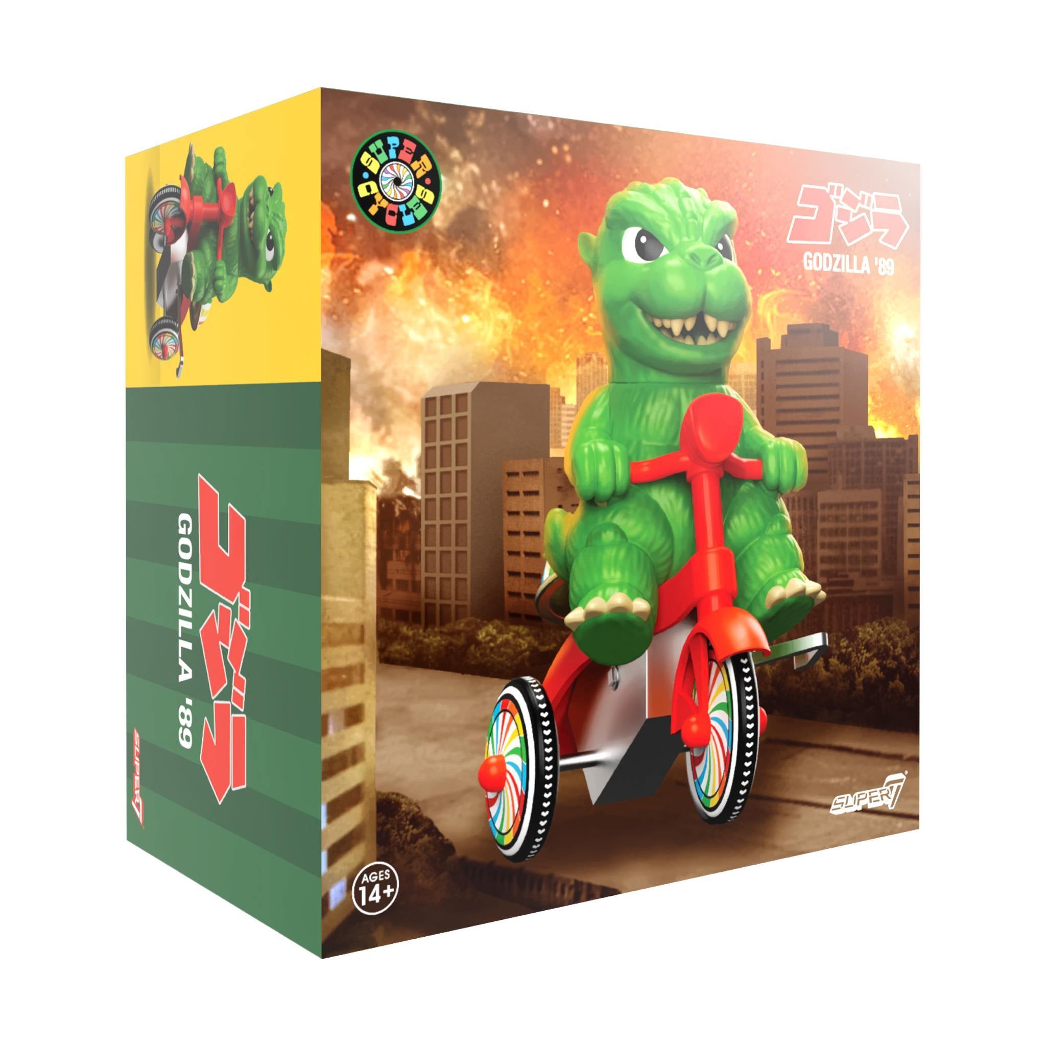 Green Godzilla riding a red tricycle on a packaged box with rainbow wheels and city scene