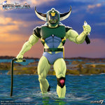 Green armored humanoid action figure with a horned helmet stands in water at sunset, holding a staff.